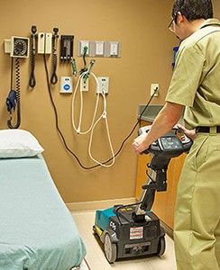 Un encargado de mantenimiento limpiando una habitación de un hospital con la restregadora de pisos cs5 de tennant